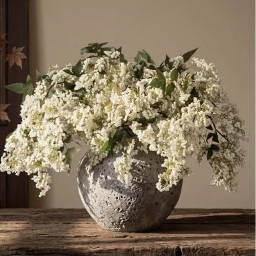 Faux white flowering branches in a textured stone vase