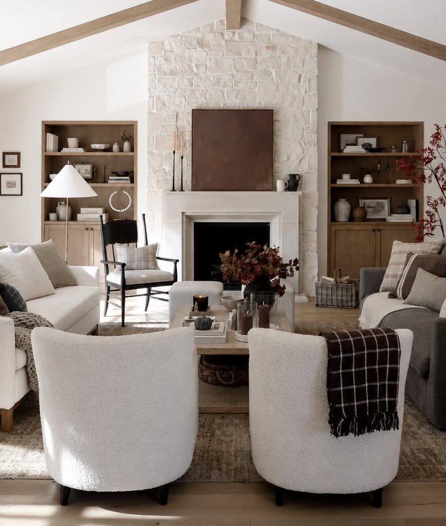 Neutral living room with a stone fireplace, boucle chairs and wood beams