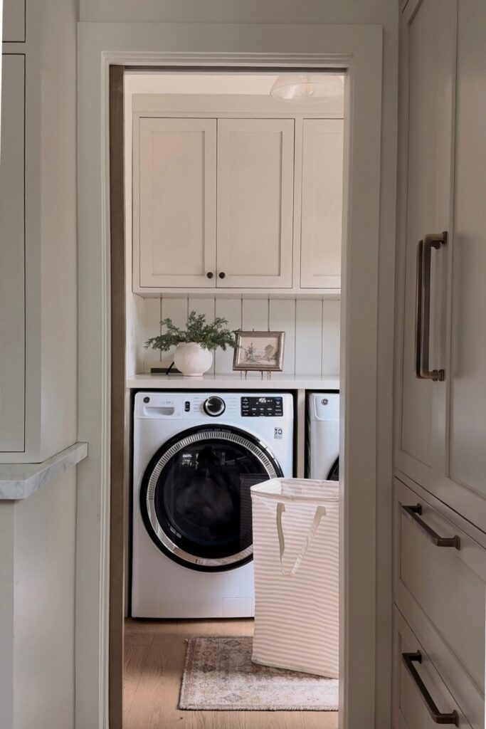 Laundry nook with a white front load washer and dryer, open shelves and glass jars